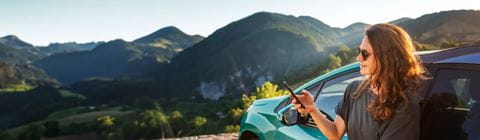 Woman using phone in front of car